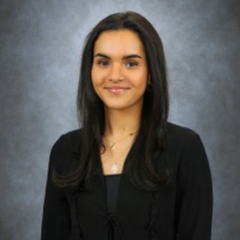 A young smiling woman with long dark hair in a black jacket / Une jeune femme souriante aux longs cheveux noirs dans une veste noire